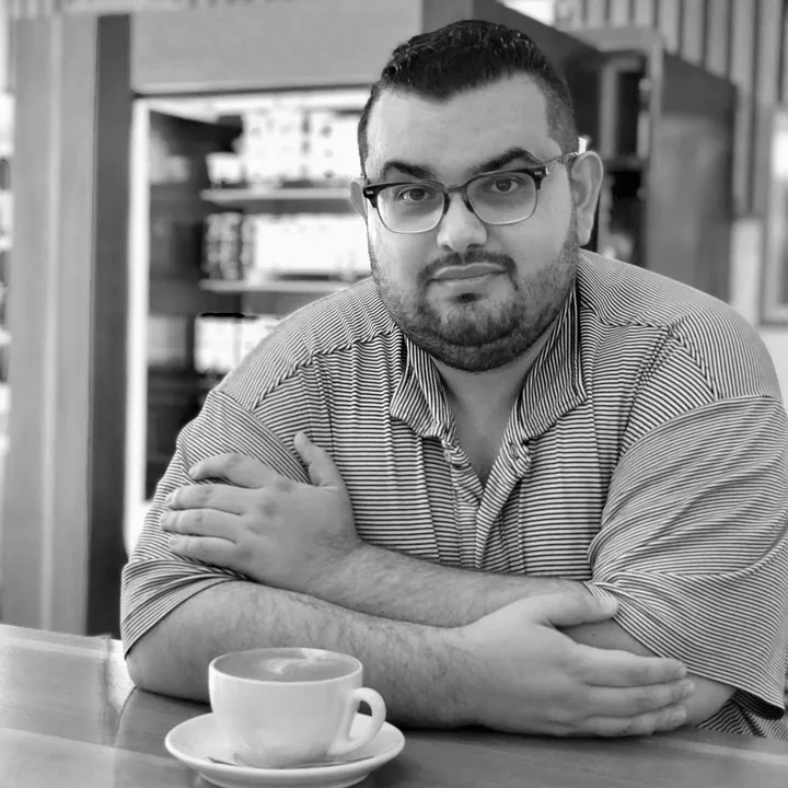 Daniel Molinares, who founded Molex Coffee, at a cafe counter with his arms folded and a cappuccino in front of him