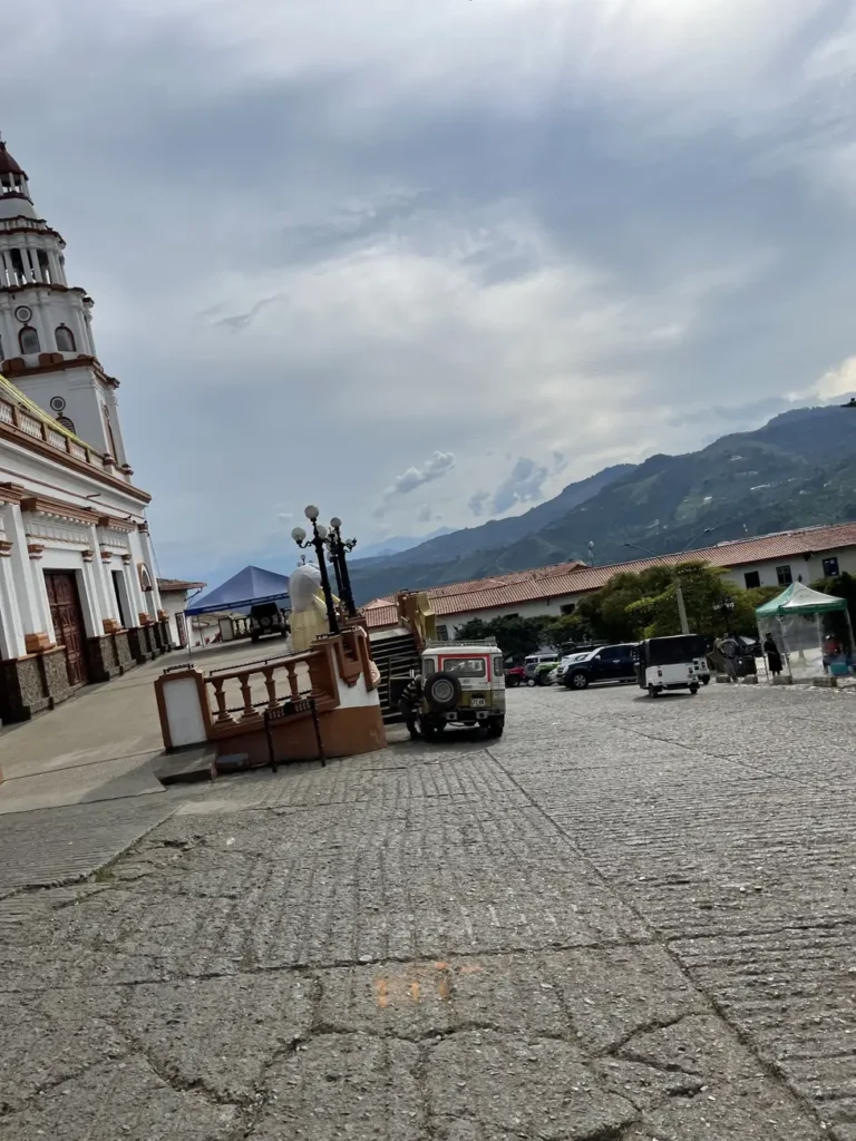 A cobbled street in Concordia leading down to the plaza, with the church tower rising behind the rooftops